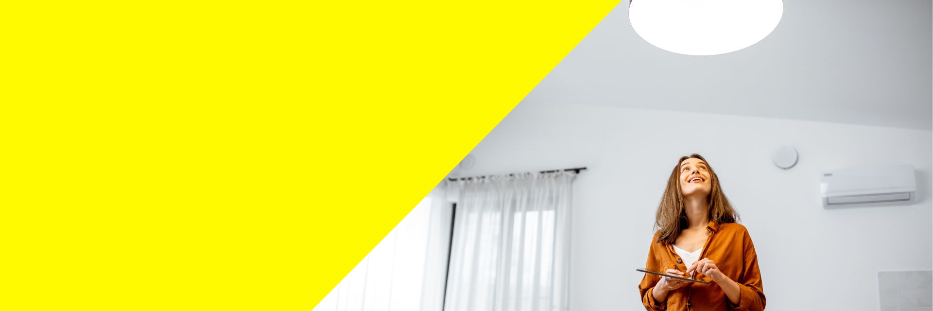 Frau bedient ihre Smarthome-Steuerung, um damit das Licht in ihrer Wohnung zu dimmen.